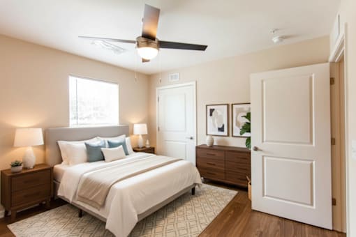 A bedroom with a bed, nightstands, and a ceiling fan.