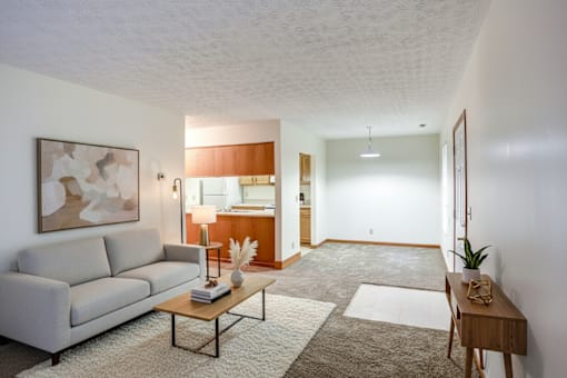 A living room with a grey couch, a coffee table, and a painting on the wall.