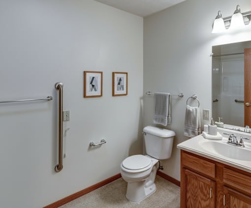 A white toilet sits in a bathroom next to a sink and a shower.