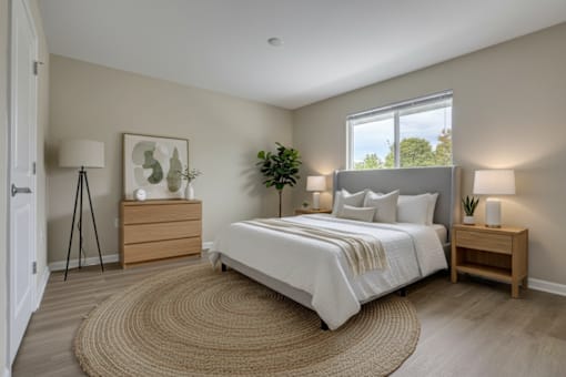 A bedroom with a large bed, a nightstand, and a rug on the floor.