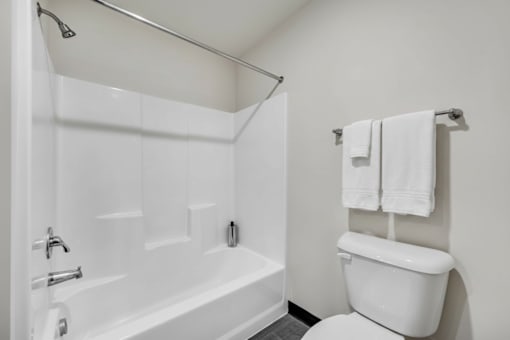 A white bathroom with a toilet, bathtub, and towel rack.