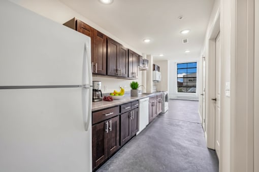 A modern kitchen with dark brown cabinets and a white refrigerator.