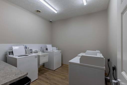 A row of white washing machines in a laundry room.