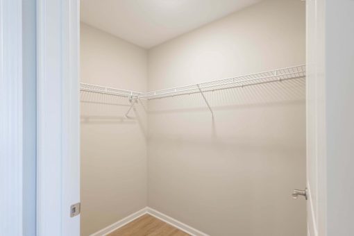 A white closet with a door on the left and a shelf on the right.