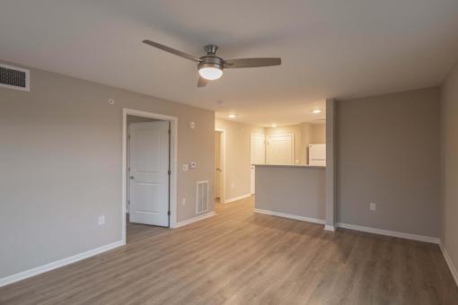 A room with a ceiling fan and light fixture, and a door leading to another room.