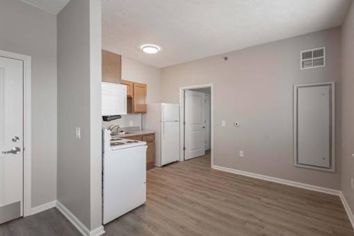 A kitchen with white appliances and wooden floors.