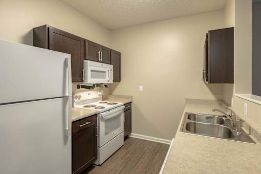 A kitchen with a white refrigerator, white stove, and white microwave.