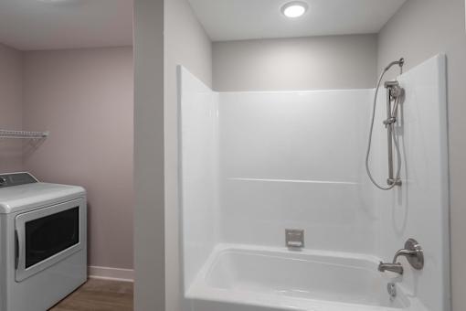 A white bathroom with a microwave and a bathtub.