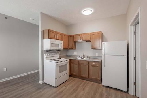 A kitchen with white appliances and wooden cabinets.