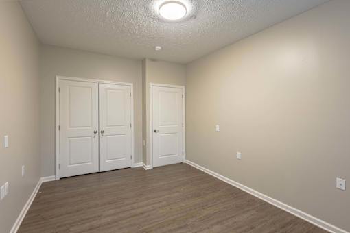 A room with two white doors and wooden flooring.
