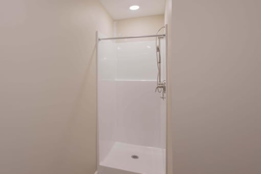 A white shower stall with a glass door and a shower head.