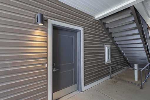 A dark grey door is on the left side of a staircase.