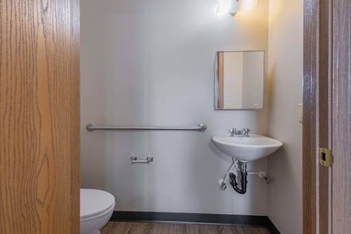 A small bathroom with a toilet, sink, and a mirror.