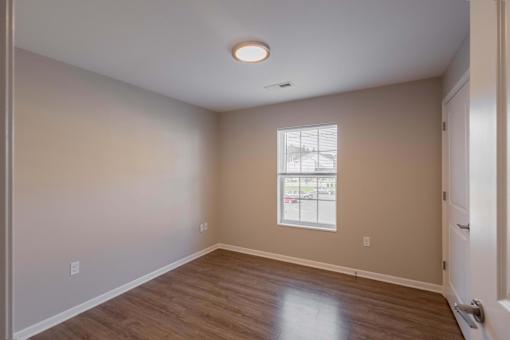 A room with a window and a wooden floor.