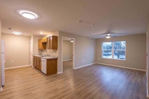A kitchen with wooden floors and a refrigerator on the left.
