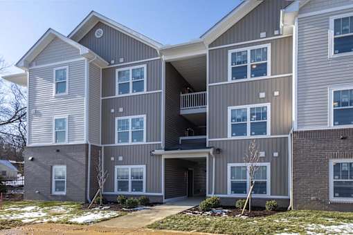 A modern two-story apartment building with a balcony on the second floor.