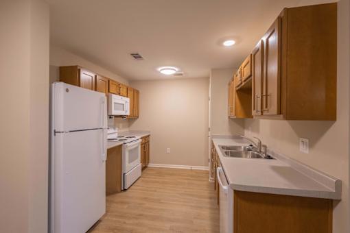 A kitchen with white appliances and wooden cabinets.