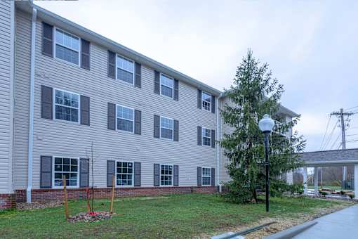 A grey building with a tree in front of it.