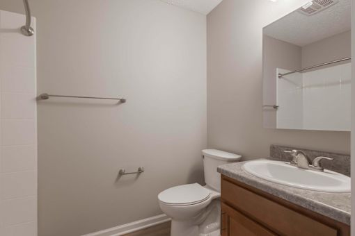 A bathroom with a toilet, sink, and a mirror.