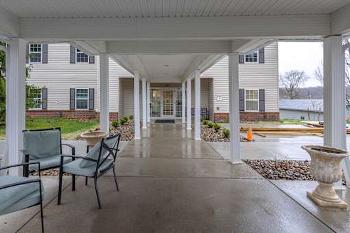 A covered porch with a table and chairs.