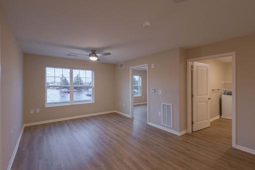 A room with a ceiling fan and a window overlooking a parking lot.