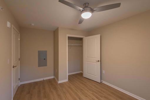 A room with a ceiling fan and a door leading to another room.