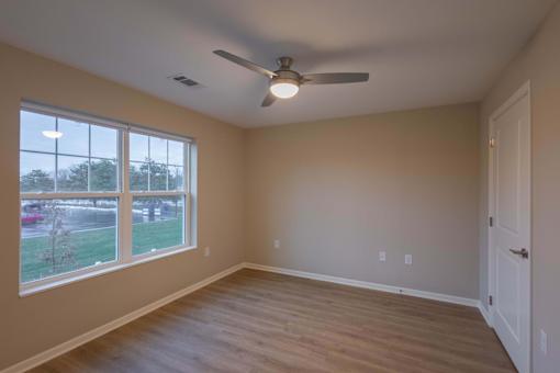 A room with a ceiling fan and a large window.