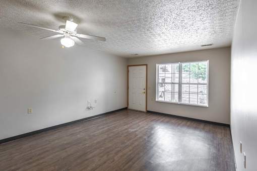 A room with a ceiling fan and wooden flooring.