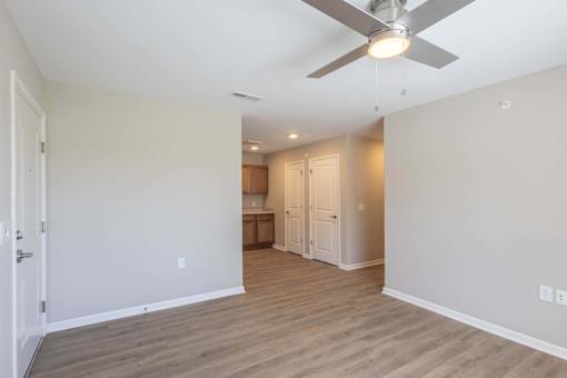 A room with a ceiling fan and wooden flooring.