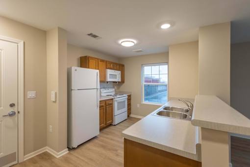 A kitchen with a white refrigerator, microwave, and oven.