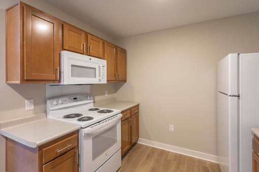 A kitchen with a white stove and a white microwave.