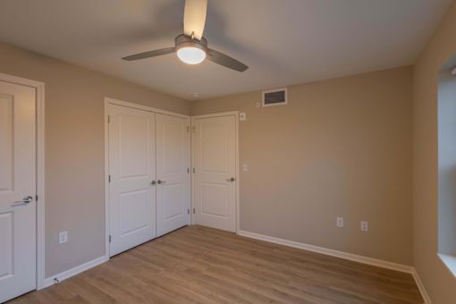 A room with a ceiling fan and wooden flooring.