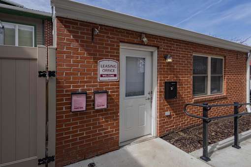 A brick building with a white door and a sign that says "Leasing Office".