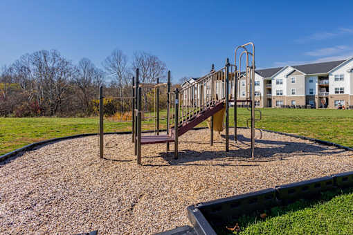 A playground with a slide and swings in a grassy area.