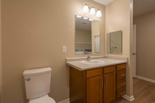 A bathroom with a toilet, sink, and mirror.