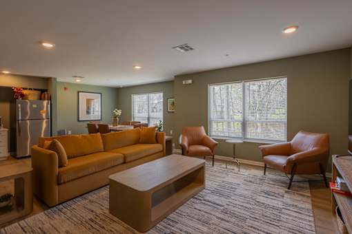 A living room with a brown couch, two chairs, and a coffee table.