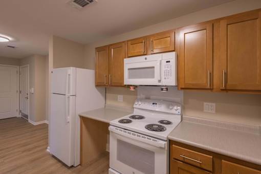 A kitchen with a white refrigerator, white microwave, and white stove.