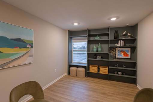 A room with a painting on the wall and a shelf with various items on it.