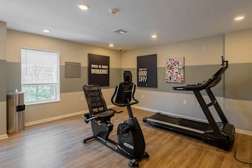 A room with a treadmill, a stationary bike, and a sign that says "Good Day" on the wall.