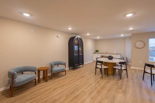 A living room with a wooden floor and a large clock on the wall.