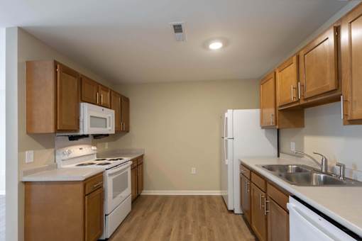 A kitchen with white appliances and wooden cabinets.
