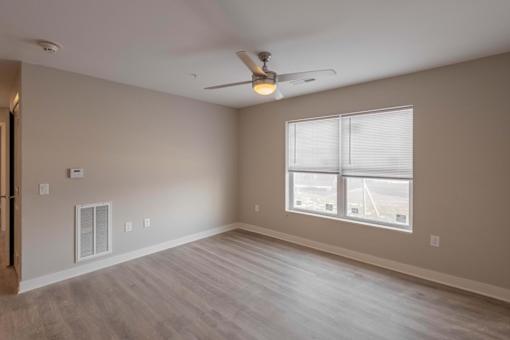 A room with a ceiling fan and a window with blinds.