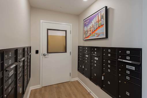 A hallway with a white door and a row of mailboxes on the wall.