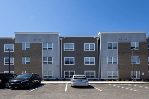 A black car is parked in front of a grey building.