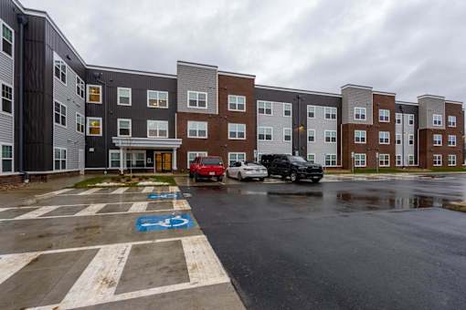 A parking lot in front of a building with cars parked.