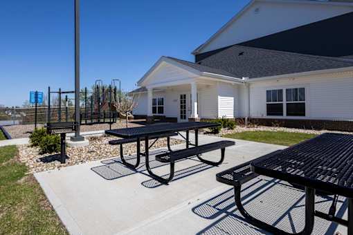 A black picnic table is in front of a white building.