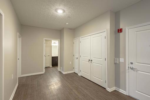 A hallway with white doors and a red fire alarm on the wall.