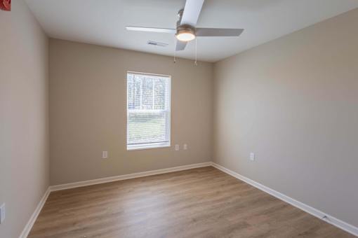 Empty room with a ceiling fan and a window.