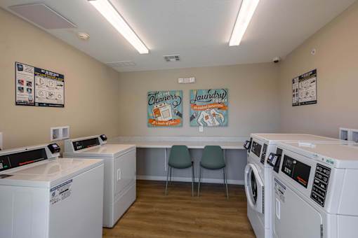 A laundromat with washers and dryers and a sign that says "Cleaners" on the wall.