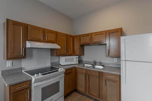A kitchen with a white refrigerator, white stove, and white microwave.